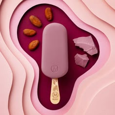 an ice cream with almonds in it on top of a pink surface and gold spoon