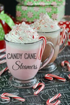 two mugs filled with candy cane steamers sitting on top of a table next to peppermints