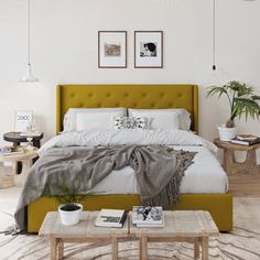 a bedroom with a bed, two tables and pictures on the wall above it that have plants in them