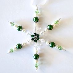 a green and white beaded snowflake ornament on a white background