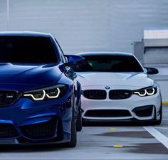 two bmw cars parked next to each other in a parking lot with yellow lines on the ground