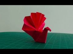 a red origami bird sitting on top of a green table