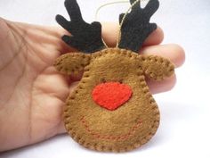 a hand holding a felt reindeer ornament with a red heart on it's nose