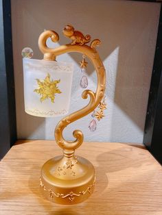 a gold lamp with a glass shade on it's base sitting on a wooden table