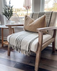 a chair sitting in front of a window next to a table with a potted plant on it