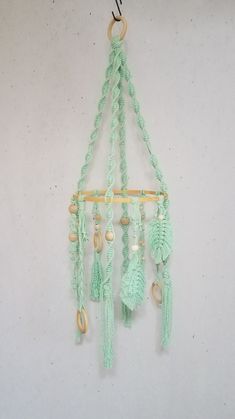 a green crocheted wall hanging with beads and tassels attached to it