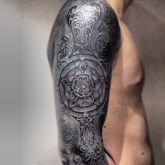 a man's arm with an intricate tattoo design on the arm and shoulder,