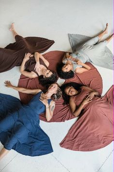 four women laying on the floor with their arms around each other and looking at the camera