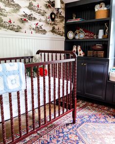 a baby's crib in the corner of a room with wallpaper on the walls