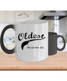 two coffee mugs sitting on top of a wooden table next to each other, with the words youngest and the favorite one