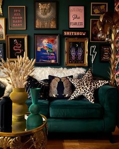 a living room filled with green couches and pictures on the wall above them in gold frames