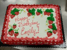 a birthday cake with strawberries on it sitting on top of a metal countertop