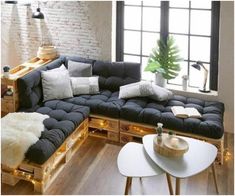 a living room filled with lots of furniture next to a brick wall and flooring