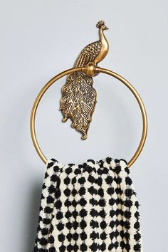 a towel rack with a peacock on it and a black and white towel hanging from the top