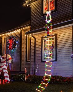 a house decorated for christmas with lights and decorations on the front yard, including a ladder