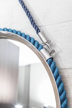 a mirror with a blue rope around it and a metal hook on the front of it