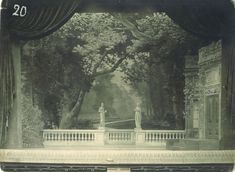 an old photo of a stage with statues on the stage and trees in the background