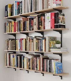 a bookshelf filled with lots of books next to a wall mounted book shelf