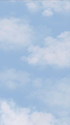 an airplane flying high in the sky with white clouds behind it and blue skies above