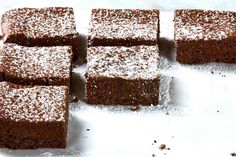 several pieces of brownie sitting on top of a white counter covered in powdered sugar