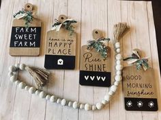 some tags are hanging on a wooden surface with white beads and tassels around them