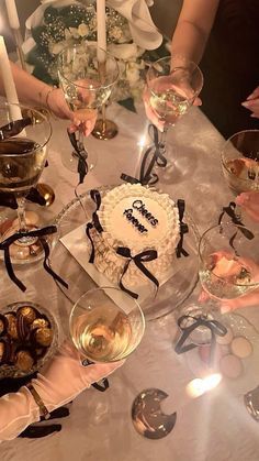 a group of people sitting around a table with cake and wine glasses on top of it