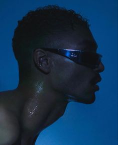 a man with sun glasses on his face in the blue light, looking to the side