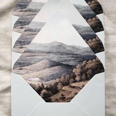 a piece of paper with mountains and trees in the background is cut out to look like an abstract painting