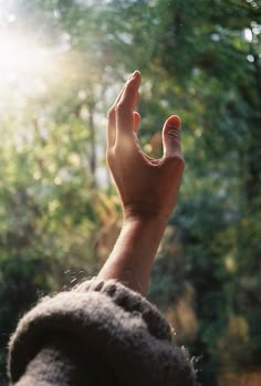 a person's hand reaching up into the air with trees in the background and text that reads never underestmate what god can do