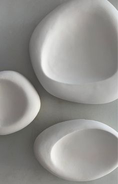 three white plates sitting on top of a table next to each other in the shape of oval shapes