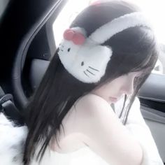 a girl in a car wearing hello kitty ears