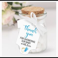 a glass jar filled with baby feet next to a bouquet of flowers and a tag that says, thank you for showering our baby with love