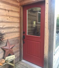 a red front door with a star on the side and a welcome sign next to it