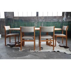 three chairs and a table in front of a green wall with cow hide rug on the floor