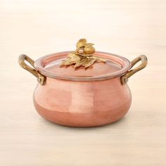 a pink pot with gold handles sitting on a table