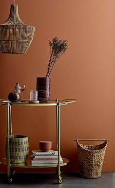 a table with baskets and vases on it in front of an orange painted wall