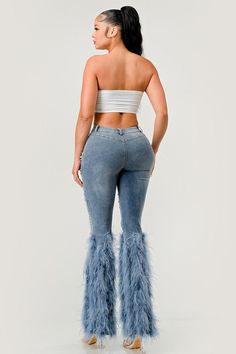 a woman in high rise jeans with feathers on the bottom and one leg, back view