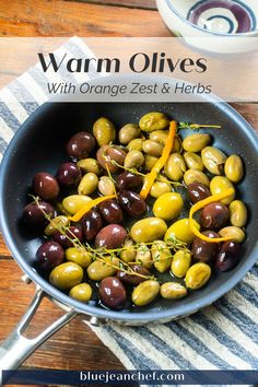 a pan filled with green and black olives on top of a striped table cloth