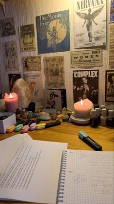 an open notebook sitting on top of a wooden table next to a lit candle and some books