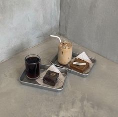 two trays with food and drink on them sitting on a counter top next to each other