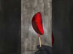 a hand holding a red candy lollipop on a stick