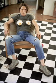 a man sitting in a chair with two donuts on his shirt and blue jeans