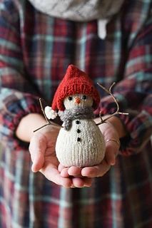 a person holding a small snowman in their hands