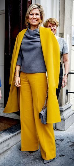 a woman wearing yellow pants and a gray top is standing in front of a door