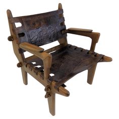 a chair made out of wood and leather with carvings on the back, sitting in front of a white background