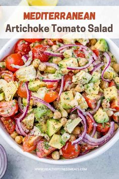 a white bowl filled with salad and topped with tomatoes, onions, avocado, cucumber, chickpeas and other veggies