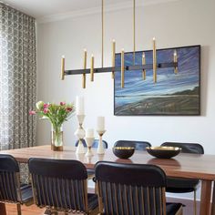 a dining room table with black chairs and a painting hanging on the wall above it