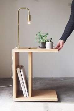 a person standing next to a table with a plant on it and a book shelf