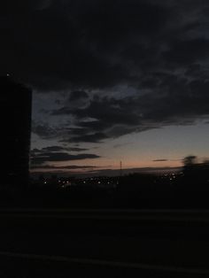 the sky is very dark and cloudy at night with some buildings in the foreground