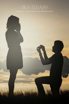 a man kneeling down next to a woman in front of a body of water at sunset